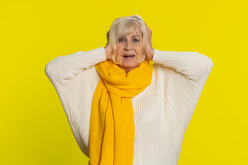 Don't want to hear and listen. Frustrated annoyed irritated senior old woman covering ears gesturing no avoiding advice ignoring unpleasant noise loud voices. Grandmother isolated on yellow background - obrazy, fototapety, plakaty