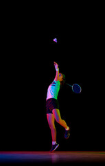 Fototapeta na wymiar Portrait of young girl, skilled badminton player practicing with intensity against black background in neon light. Concept of sport, active, healthy lifestyle, strength and power, action. Copy space.