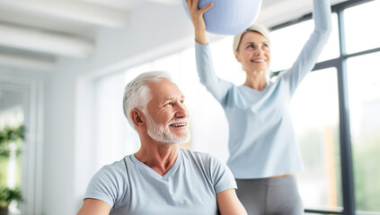 Senior citizens engaging in physical exercise, a man with a gym ball and a woman stretching against...