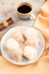 traditional arabic sweets pishmanie and a cup of coffee on brown concrete, side view, selective focus.