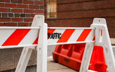 orange street construction cone on road with blurred background, symbolizing caution and ongoing...