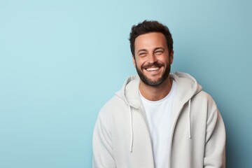 Portrait of a happy man in his 30s wearing a zip-up fleece hoodie against a pastel or soft colors...