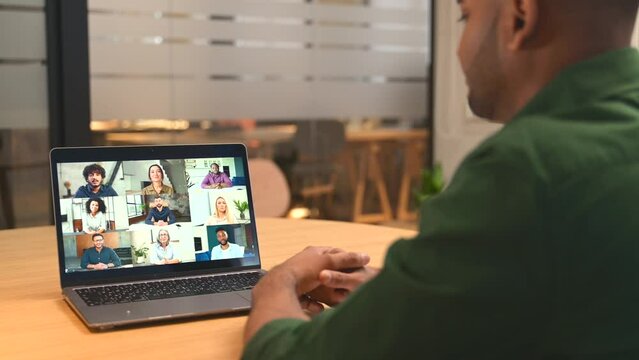 Young indian man using laptop for virtual meeting with colleagues, brainstorming with a multiracial team online, group of diverse people on the screen. App for video communication, video call concept