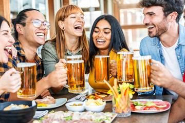 Multiethnic happy friends drinking beer glasses sitting at brewery pub restaurant table - Smiling guys and girls having fun at rooftop dinner party - Food and beverage lifestyle
