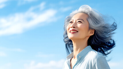 Naklejka premium Happy Elderly Japanese Woman with Gray Hair Looks Into the Blue Sky
