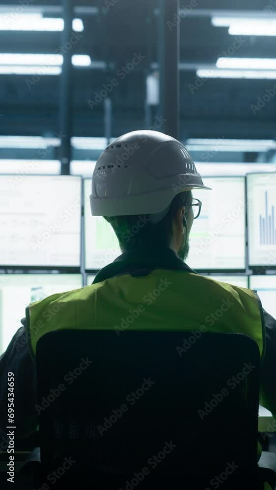 Poster Vertical Screen: Backview To Close Up Of Caucasian Male Engineer Using Multi Monitor Workstation To Control Production on Assembly Line With Robotic Arms. Man Adjusting Manufacturing Processes.