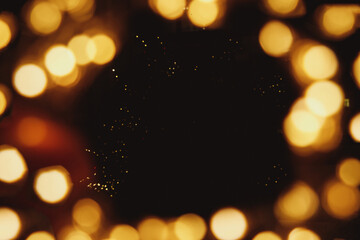 Frame with golden light bokeh on black background. Festive mock up. Defocused, blurred lights, yellow spots. Christmas, birthday party, holiday, romantic card concept. Copy space.glitter texture