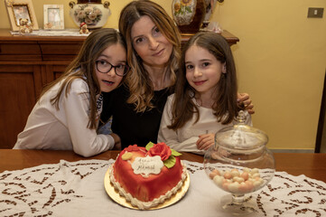 Mamma con le figlie gemelle di nove anni e torta di auguri per la mamma.