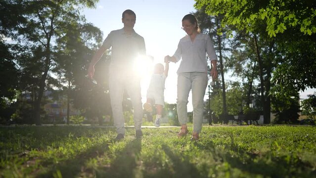 happy family. parents and baby walking in the park holding hands silhouette. happy family kid dream concept. friendly family and baby are resting in nature walking in lifestyle the woods couple