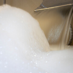 Selective focus on water flow. Bubble white foam of soaps in bathtub.