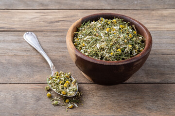 Chamomile dried tea leaves and flowers on a bowl over wooden table