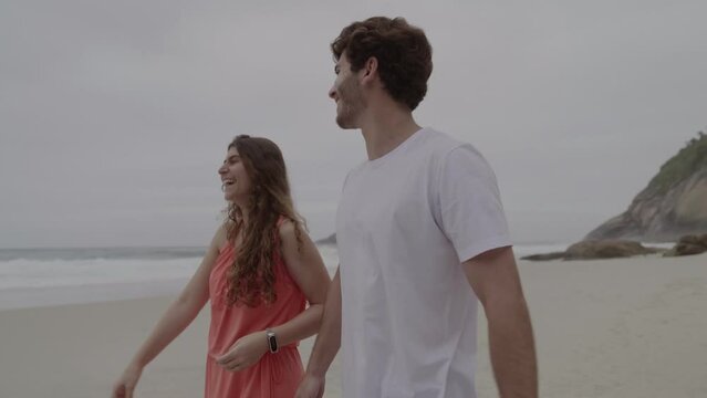 Casal conversando, caminhando pela praia.