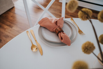 bright white dinning room table plated with gold utensils  - obrazy, fototapety, plakaty