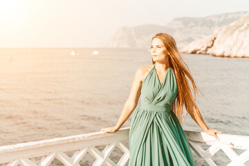 Woman sea trevel green dress. Side view a happy woman with long hair in a long mint dress posing on a beach with calm sea bokeh lights on sunny day. Girl on the nature on blue sky background.