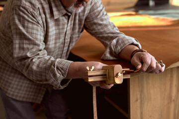 hardworking professional craftsman cutting leather with special tool. close up cropped photo. focus on cutting process, man's arms
