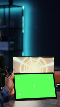 Vertical video Woman invited to podcast watching internet clips on green screen tablet with host in studio, discussing content. African american guest reacting to videos on mockup device during online