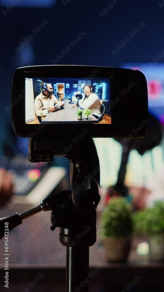 Poster vertical video focus on professional camera used to record radio show presenter live conversation wi