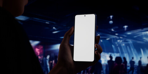 Caucasian woman holding phone, night club in the background, blank screen mockup
