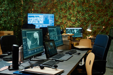 Part of spacious office of secret service with group of computer screens with various data on...