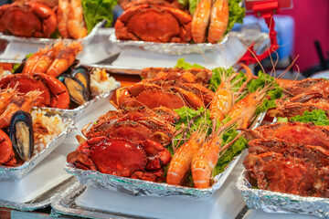 Large crabs and king prawns with green salad from dishes on a street food stall.