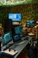 Desk with group of computer monitors with graphic data on screens standing in front of camera in...