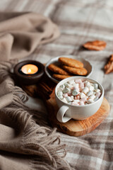 Fototapeta na wymiar warm cozy bedroom interior with cup of hot chocolate on tray, candles christmas lights