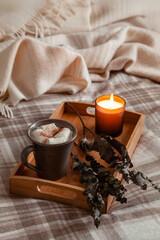 warm cozy bedroom winter or autumn concept, cup of hot chocolate on tray, candles throw