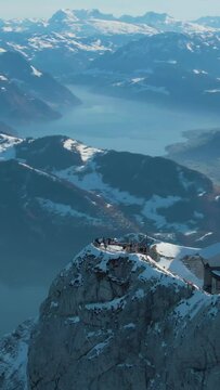 Mountain Pilatus Viewpoint, Lake and Lucerne City in Winter Morning. Tourists on Viewpoint. Swiss Alps, Switzerland. Aerial View. Drone is Orbiting. Vertical Video