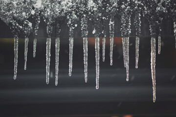 Icicles hang on the roof of a house. Spring landscape with icicles hanging from the roof of the...