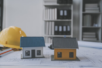 architectural model of houses on desk with drawing technical tools and blueprint rolls, isolated on...