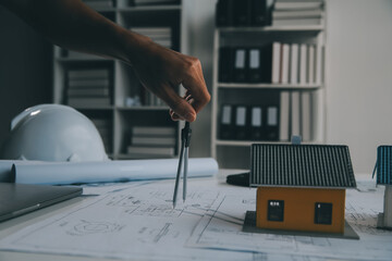 architectural model of houses on desk with drawing technical tools and blueprint rolls, isolated on...