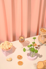 Table with drink, cookies and flowers. Peach colored curtains in the background. High angle view.