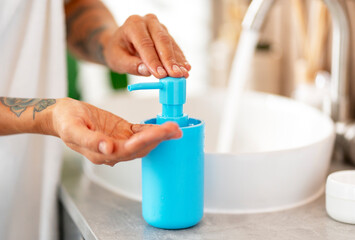 Young woman washing her hands with liquid soap in blue jar, mockup, in bathroom, closeup - obrazy, fototapety, plakaty