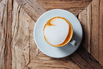 Cup of freshly made delicious cappuccino coffee with fluffy foam on rustic wooden background, view...