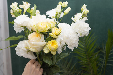 Floristry. Flowers. A florist girl collects a bouquet of white and yellow roses. Blurred background.