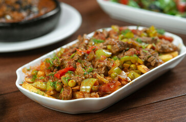 Beef stewed with vegetables and herbs in a white plate.