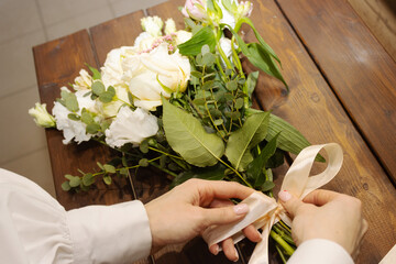 Floristry. Flowers. A florist girl collects a bouquet on the desktop, brown in color.