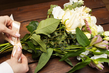 Floristry. Flowers. A florist girl collects a bouquet on the desktop, brown in color.