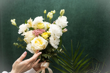 Floristry. Flowers. A florist girl collects a bouquet of white and yellow roses. Blurred background.