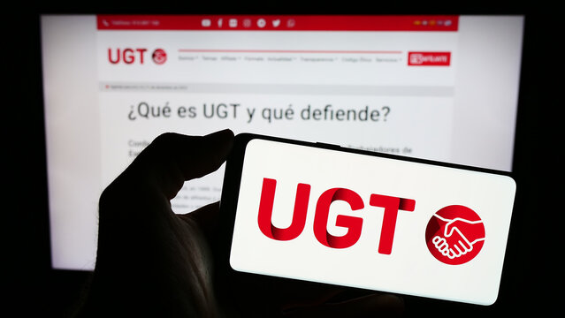 Stuttgart, Germany - 12-07-2023: Person holding mobile phone with logo of Spanish Uni&oacute;n General de Trabajadores (UGT) in front of web page. Focus on phone display.