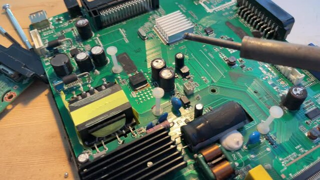 Close up Soldering a micro chip processor with iron tool on a green circuit boad. Electroncs service technology and macro computer concept background.