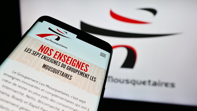 Stuttgart, Germany - 12-08-2023: Mobile phone with website of French company ITM Entreprises S.A. (Les Mousquetaires) in front of logo. Focus on top-left of phone display.