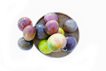 isolated Passion fruit in a bamboo basket on white background. The passion fruit has an oval shape, a thick, oily rind. There are many seeds inside the fruit. It is a healthy fruit with high fiber.