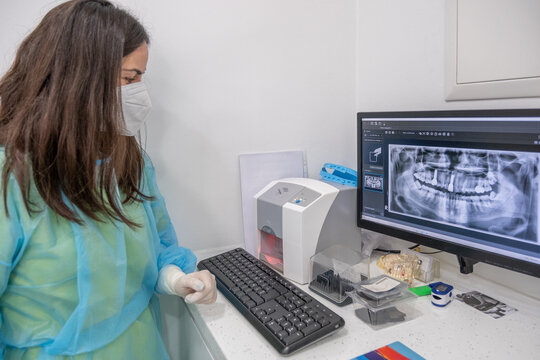 A dental assistant checking an X-ray on a computer screen.