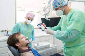A dentist and his assistant taking pictures of a patient's mouth with a special light.