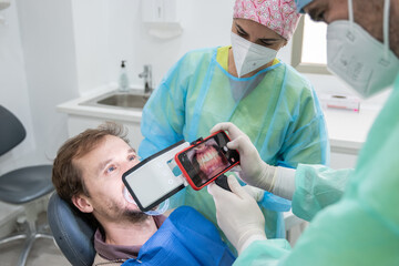 A dentist and his assistant taking pictures of a patient's mouth with a special light.