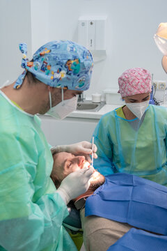 A patient undergoing a dental check-up in a clinic with the dentist in attendance and all the tools of dental care.