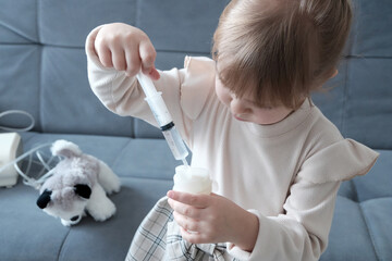 A little bright girl treats her soft toys with a nebulizer inhaler, puts a mask on her teddy...