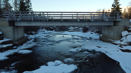 Small snowy bridge over clean cold winter fresh water stream in northern norway