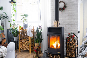 Metall black stove, burning hearth fireplace in white Festive interior of house is decorated for...